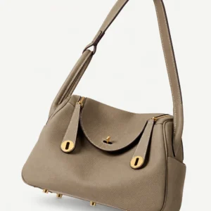 Taupe grained leather satchel with shoulder strap, rounded flap and gold-tone hardware