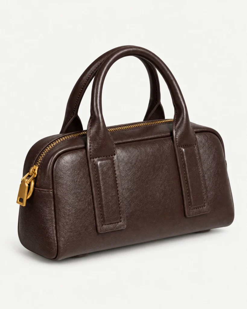 Coffee compact leather bowling bag on a pale studio background