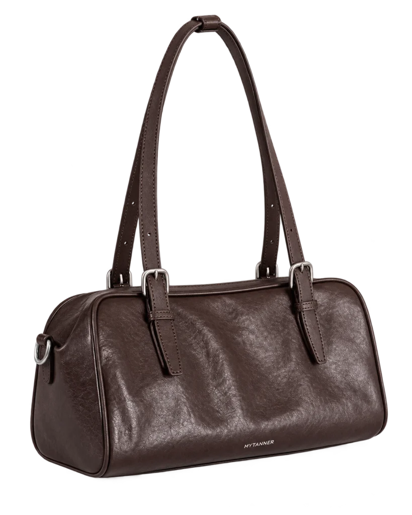 Coffee leather bowling shoulder bag on a pale studio background