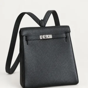 Black grained leather backpack with silver-tone closure, resting on a pale studio surface