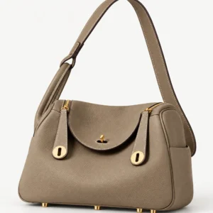 Taupe folded leather satchel standing level on its gold-tone feet