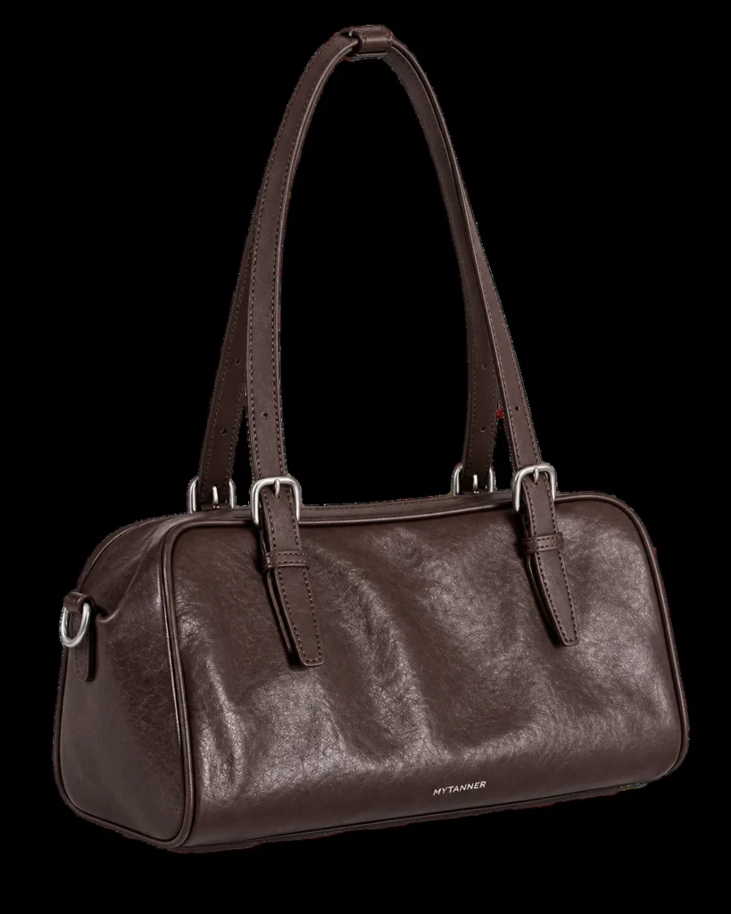 Coffee leather bowling shoulder bag on a pale studio background
