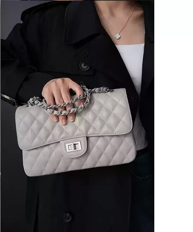 MONA STUDIO pearl gray quilted chain flap bag carried by hand with black outerwear